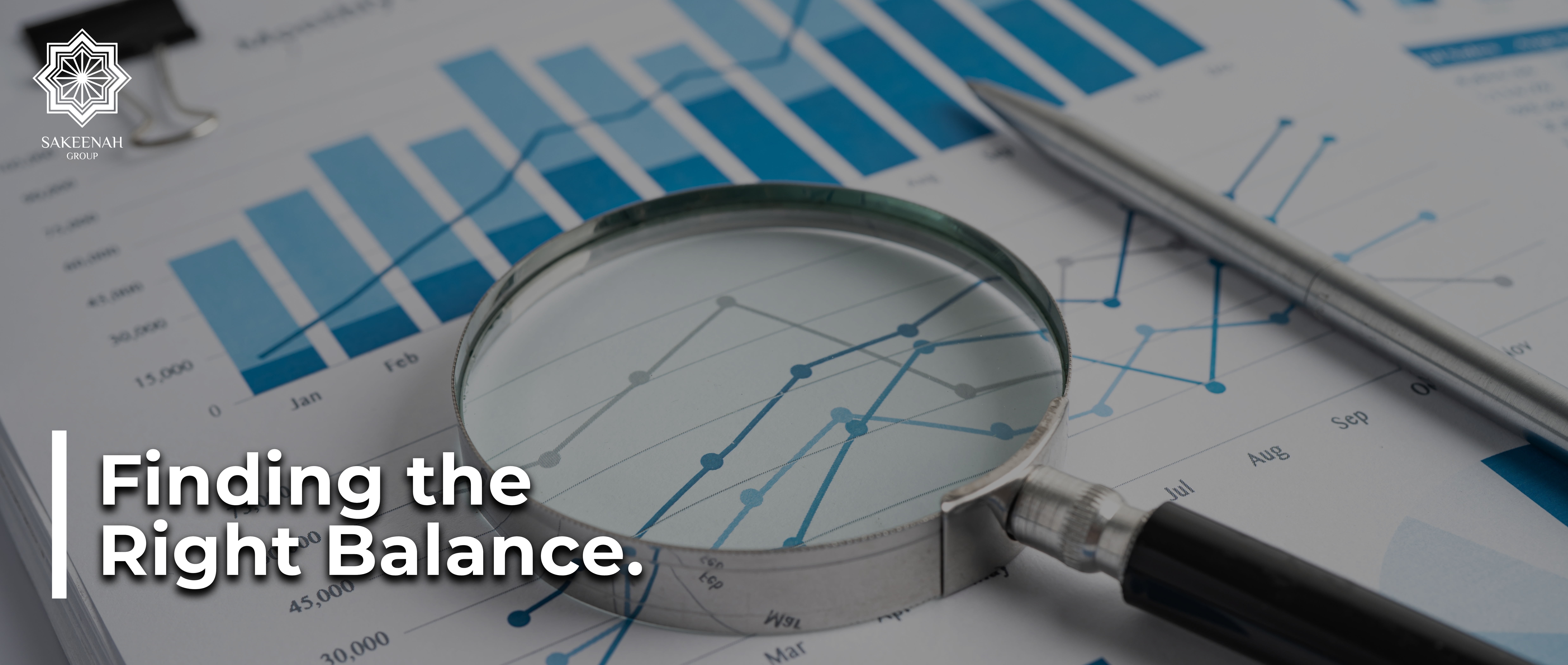 A close-up shot of financial charts and graphs with a slight dark overlay. A silver magnifying glass lies in the center, focusing on intersecting blue line graphs, with a silver pen resting to the right. In the background, a blue bar chart shows monthly progression. The white text 'Finding the Right Balance' is superimposed on the bottom-left corner, and the white 'SAKEENAH GROUP' logo is visible in the top-left corner.